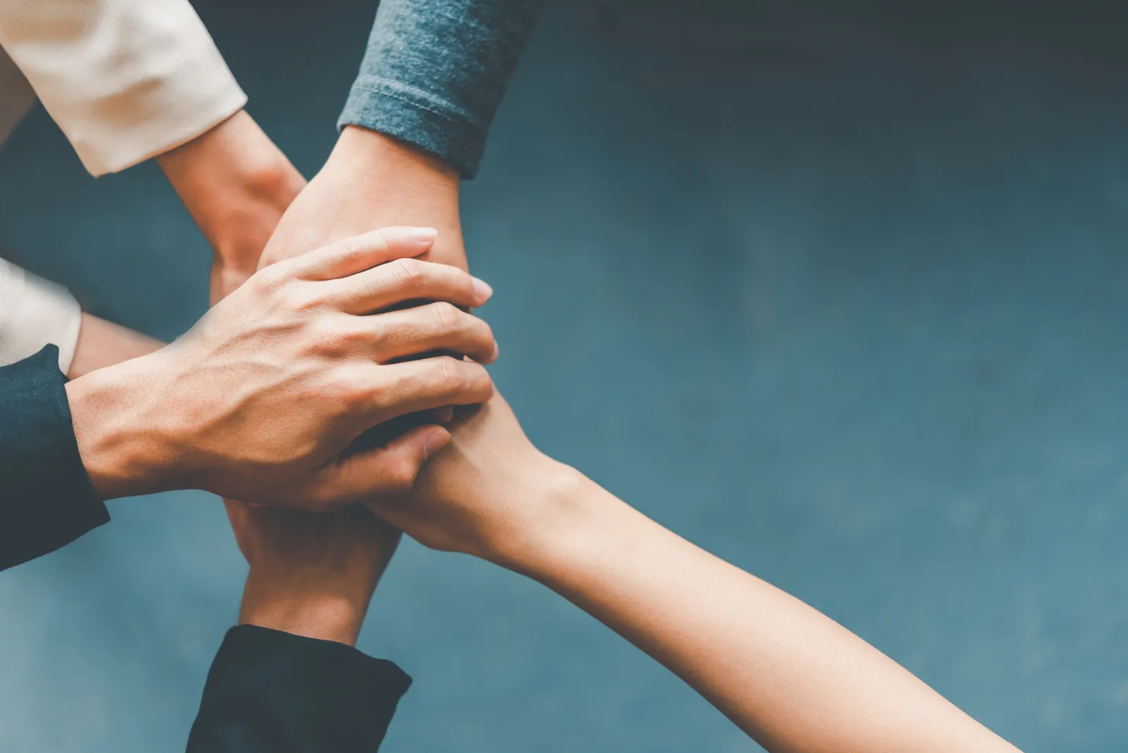 Team members joining hands, representing Sri Suria's shared values